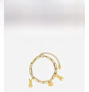 Detail of gold double-layer bracelet with mechanical rabbit charms and heart pendant