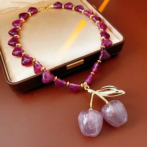 Detail of acrylic cherry pendant necklace with glitter resin and purple bead chain