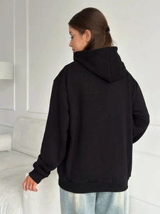 Back view of a black oversized fleece hoodie showing its loose fit and ribbed hem details