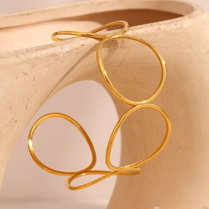 Artistic detail of 18K gold plated minimalist multi-layer circular open bangle on ceramic