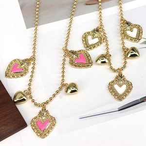 Close-up of golden beaded necklaces with pink and white enamel sacred heart pendants