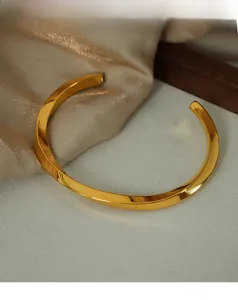 Close-up of twisted gold plated titanium steel open bangle with a polished mirror finish