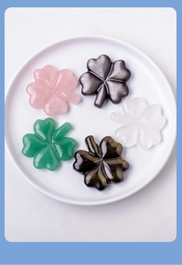Close-up of five carved crystal four-leaf clovers in a white tray for home decor
