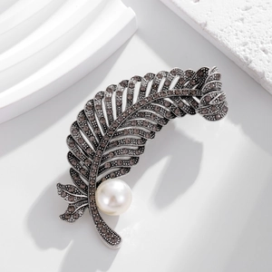 Macro detail of vintage silver feather brooch with marquise stones and large pearl
