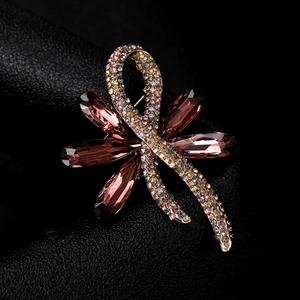 Close-up of golden dragonfly brooch with large brown gems and colorful rhinestones