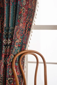 Detail of bohemian jacquard curtain with geometric patterns and white fringe tassels