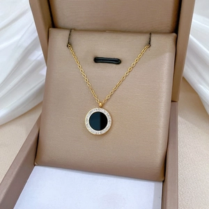 Detail of round black agate pendant necklace with pavé stones in a gold jewelry box