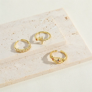 Set of three vintage gold cross rings with zircons on elegant beige stone travertine