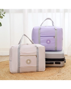 Detail of travel duffel bags in beige and lavender colors placed on a silver suitcase