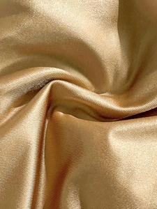 Vista macro de tela de bikini de satén oro champán con textura de canalé fino y brillo metal