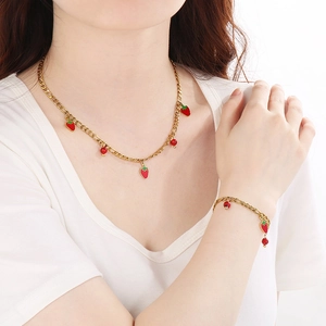 Detail of 18K gold-plated necklace set with red enamel strawberry and stone charms