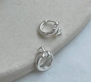 Minimalist 925 sterling silver bow knot hoop earrings on a textured stone surface