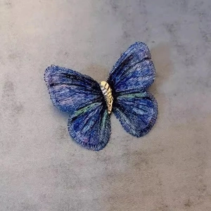 Elegant butterfly brooch with blue embroidery and gold metal details in a minimalist style