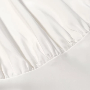 Gros plan sur le tissu en satin blanc montrant d'élégants drapés et une texture soyeuse