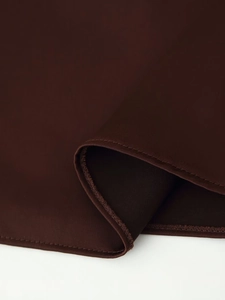 Detailed close-up of dark chocolate satin fabric with professional overlock stitching
