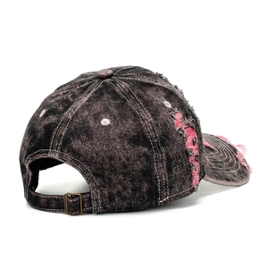 Detailed side view of distressed denim baseball cap with pink frayed edges and metal buckle