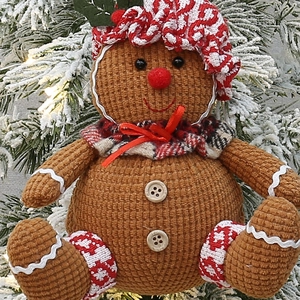 Gingerbread man plush ornament with striped hat and scarf on a snowy Christmas tree
