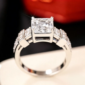 Macro view of square princess cut ring with intricate four-prong setting and side diamonds