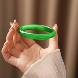 Detailed close-up of emerald green cat-eye stone bangle with smooth round-bar texture