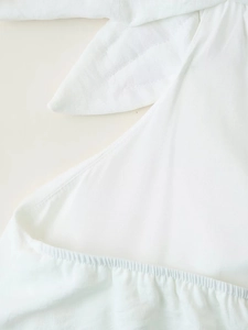 Gros plan sur le tissu blanc avec nœud décoratif et détails de plis élastiques élégants