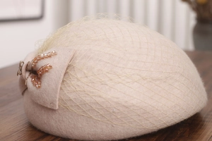 Detailed close-up of wool beret featuring elegant mesh veil and pearl beaded floral decor