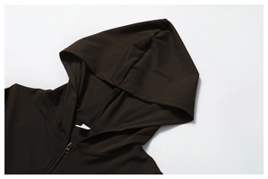 Detail of dark brown hooded jacket featuring smooth zipper and premium athletic fabric