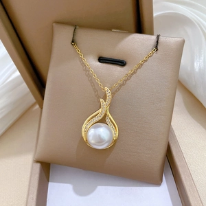 Detailed shot of gold fishtail pearl pendant with sparkling diamonds in a jewelry box