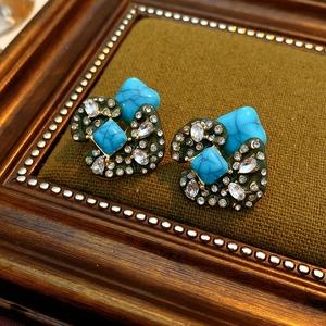 Macro detail of vintage turquoise earrings with crystals on dark green velvet background