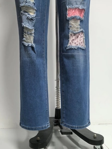 Dettaglio dei jeans blu strappati con toppe leopardate rosa e bordi sfilacciati a mano