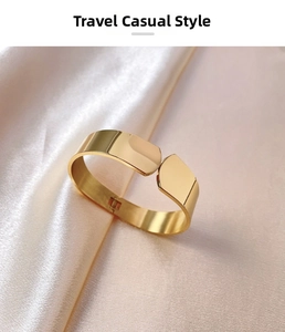 Close-up of gold titanium steel bangle with shield ends on champagne silk background