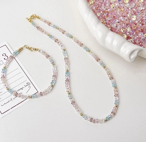 Detail of beaded jewelry set with pink and blue faceted crystal glass beads and gold spacers