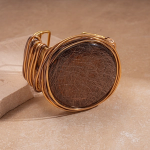 Detailed macro view of retro bohemian woven bangle with golden wire and brown center piece