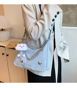 Detail of light blue crescent bag with pleated fabric, butterfly charm and cloud pendant