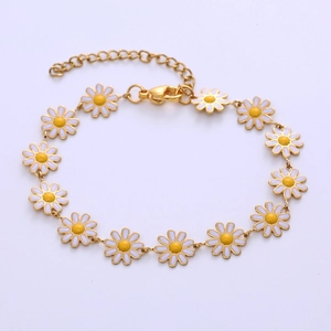 Macro detail of bohemian golden chain bracelet featuring white enamel daisy flower charms