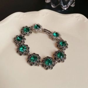 Détail d'un bracelet en argent avec fleur en pierre verte sur une assiette