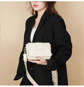 Detailed shot of white woven leather crossbody bag with geometric pattern wide strap