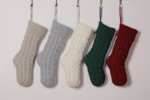 Row of five colorful cable knit Christmas stockings hanging on gold wall hooks
