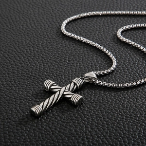 Collana vintage in acciaio inossidabile con pendente a croce rigata su sfondo in pelle nera