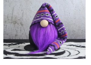 Detail of Halloween gnome featuring a purple knitted hat and purple beard on textured fabric