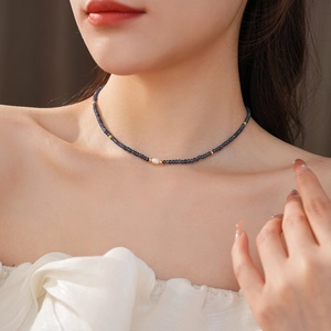 Detail of beaded choker featuring a white pearl and gold spacers on a female neck