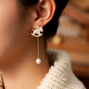 Detail of 18k gold plated rocking horse earring with tassels and a white pearl