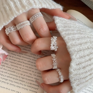 Detail of five-piece silver ring set with lace flower patterns and pearl accents on hand