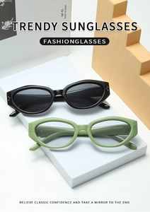 Detail of stylish wide-frame cat-eye sunglasses in black and olive green on a white tray