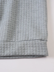 Close-up of grey waffle knit fabric texture on long sleeve hoodie sweatshirt hem