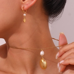 Golden shell pendant necklace and pearl earrings set shown worn by a female model