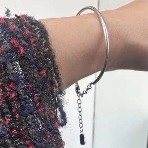 Detail of silver geometric minimalist bangle with black pendant on model's wrist