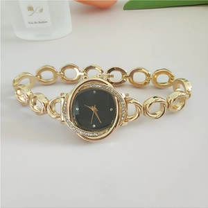 Detail of gold floral watch with black dial and crystal bezel on a chain bracelet