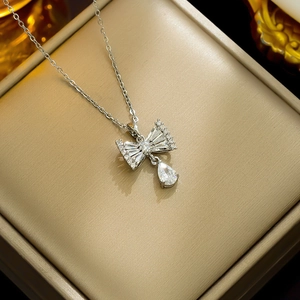 Silver bow necklace with teardrop zircon pendant displayed on a premium gold jewelry box