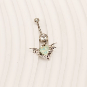 Macro view of winged heart belly ring featuring light green cat eye stone and clear zircon