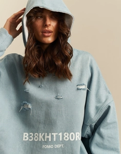Close-up of distressed denim-textured hoodie with white FOMO DEPT lettering